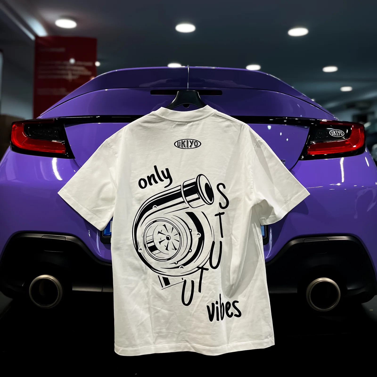 T-shirt UKIYO bianca con la grafica di una turbina e la scritta “only lost STUTU vibes”.