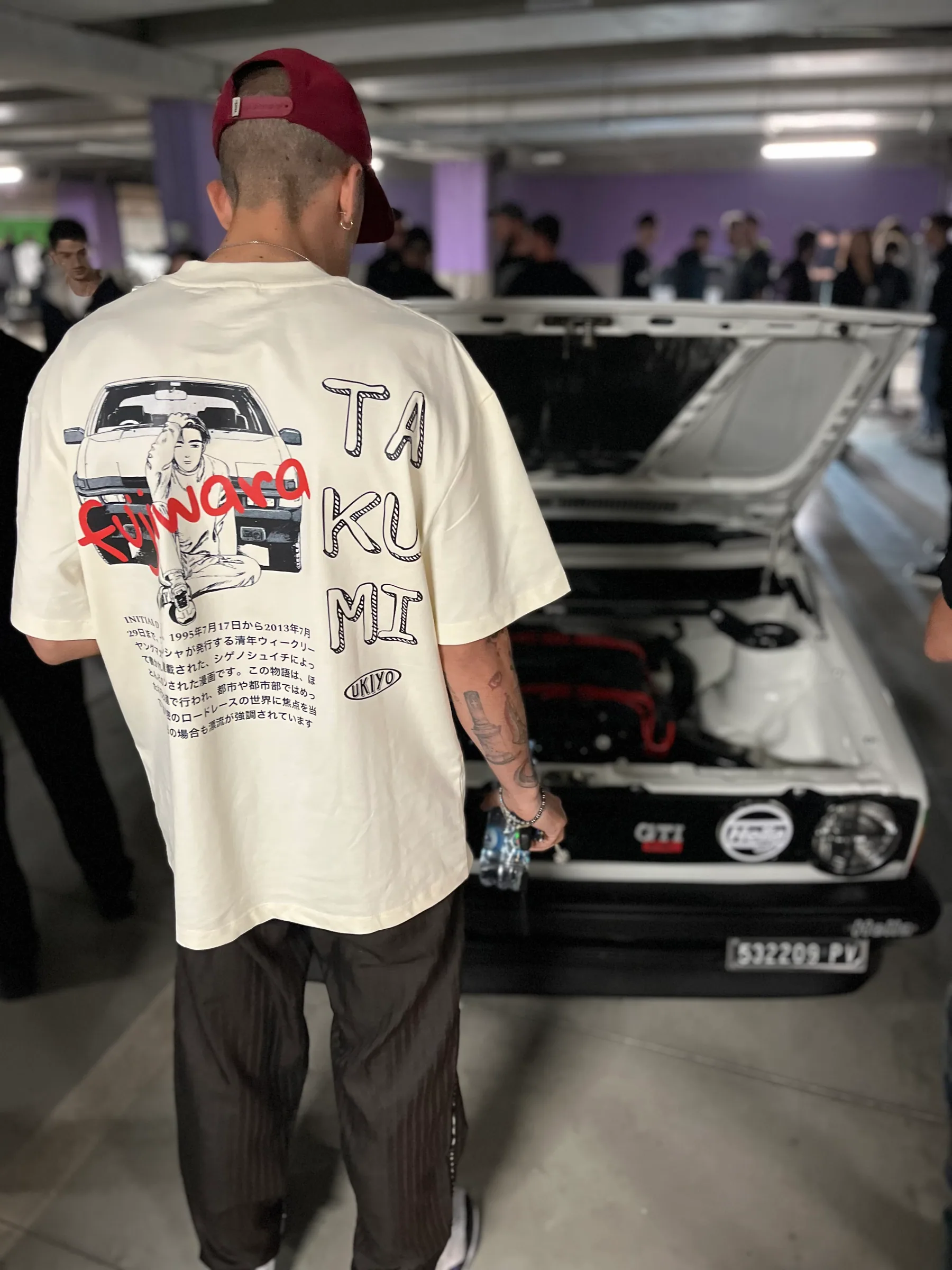 Un ragazzo di spalle indossa una t-shirt UKIYO “Takumi” durante un raduno in un garage.
