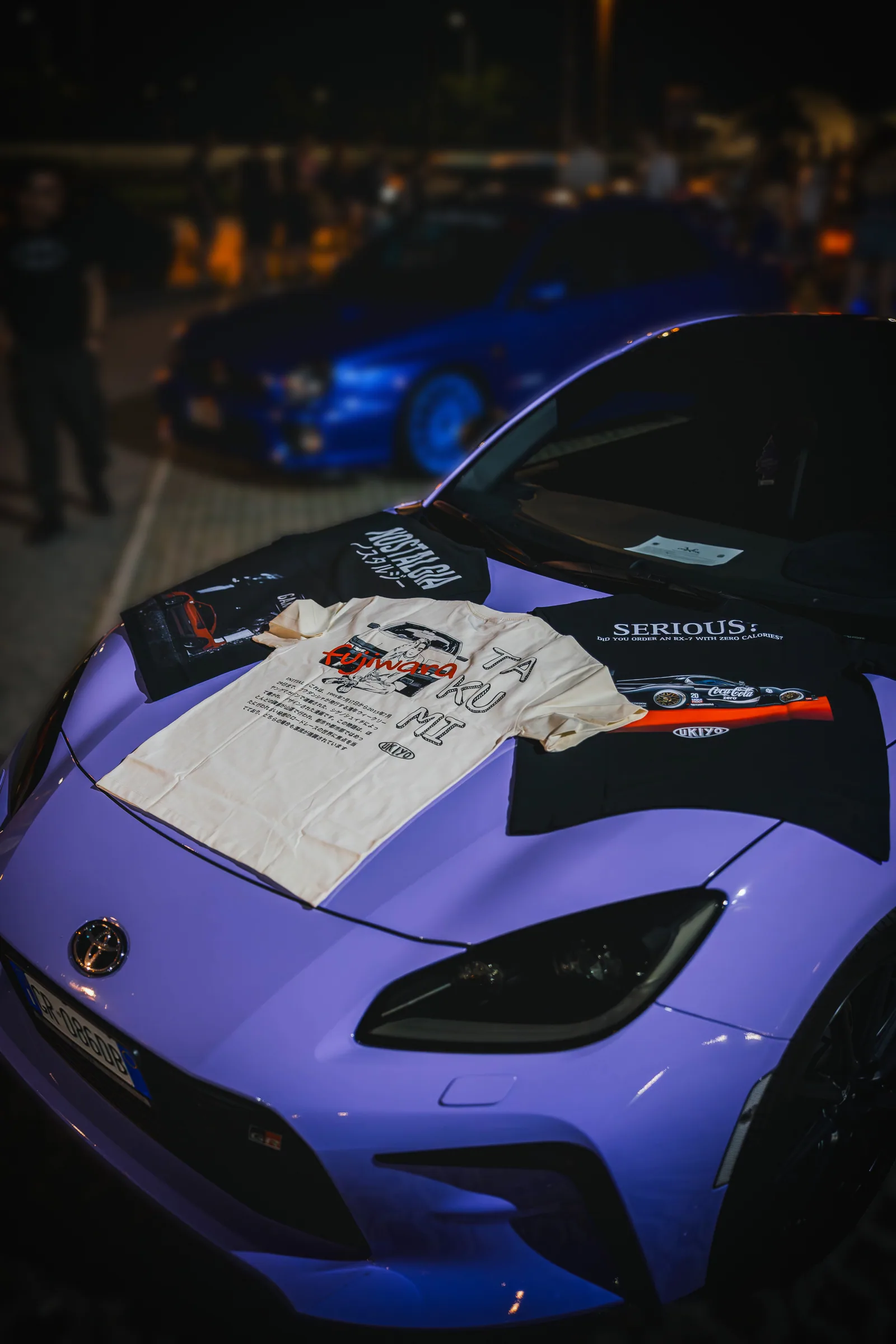 Il frontale di una Toyota GR86 lilla fotografata di notte.