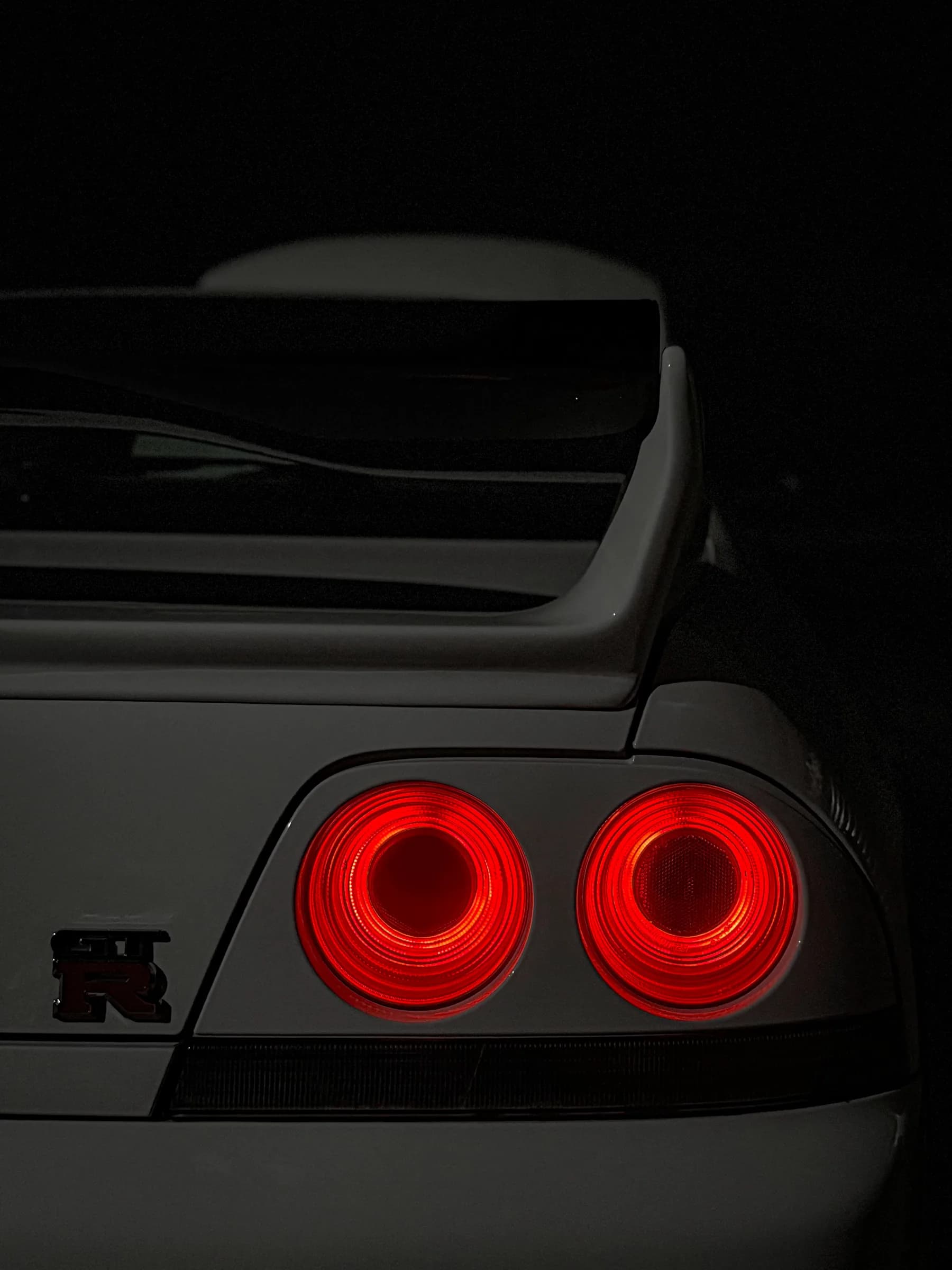I fari posteriori circolari di una Nissan Skyline R33 accesi nel buio.